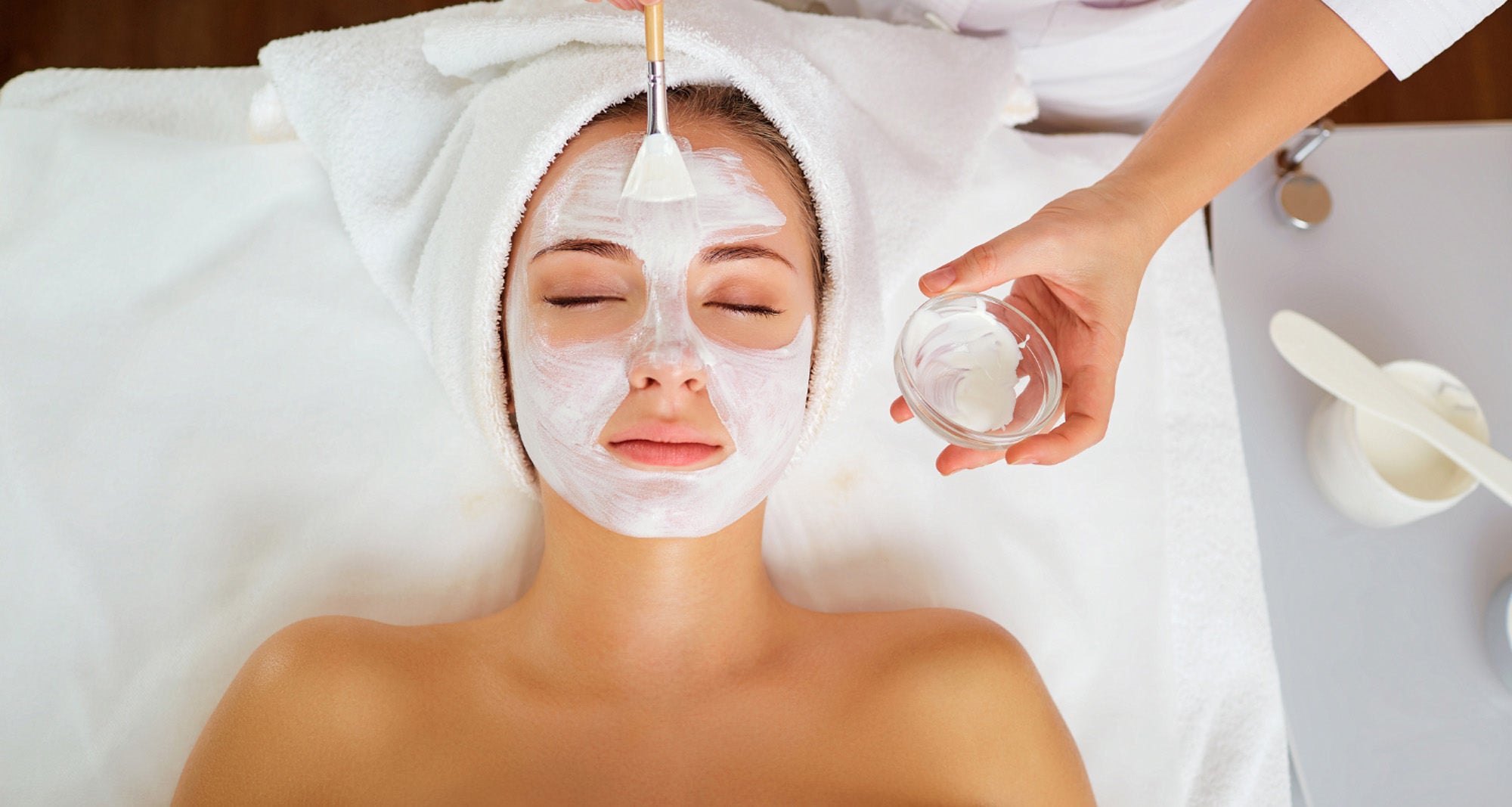 girl getting a facial with someone brushing cream on her face